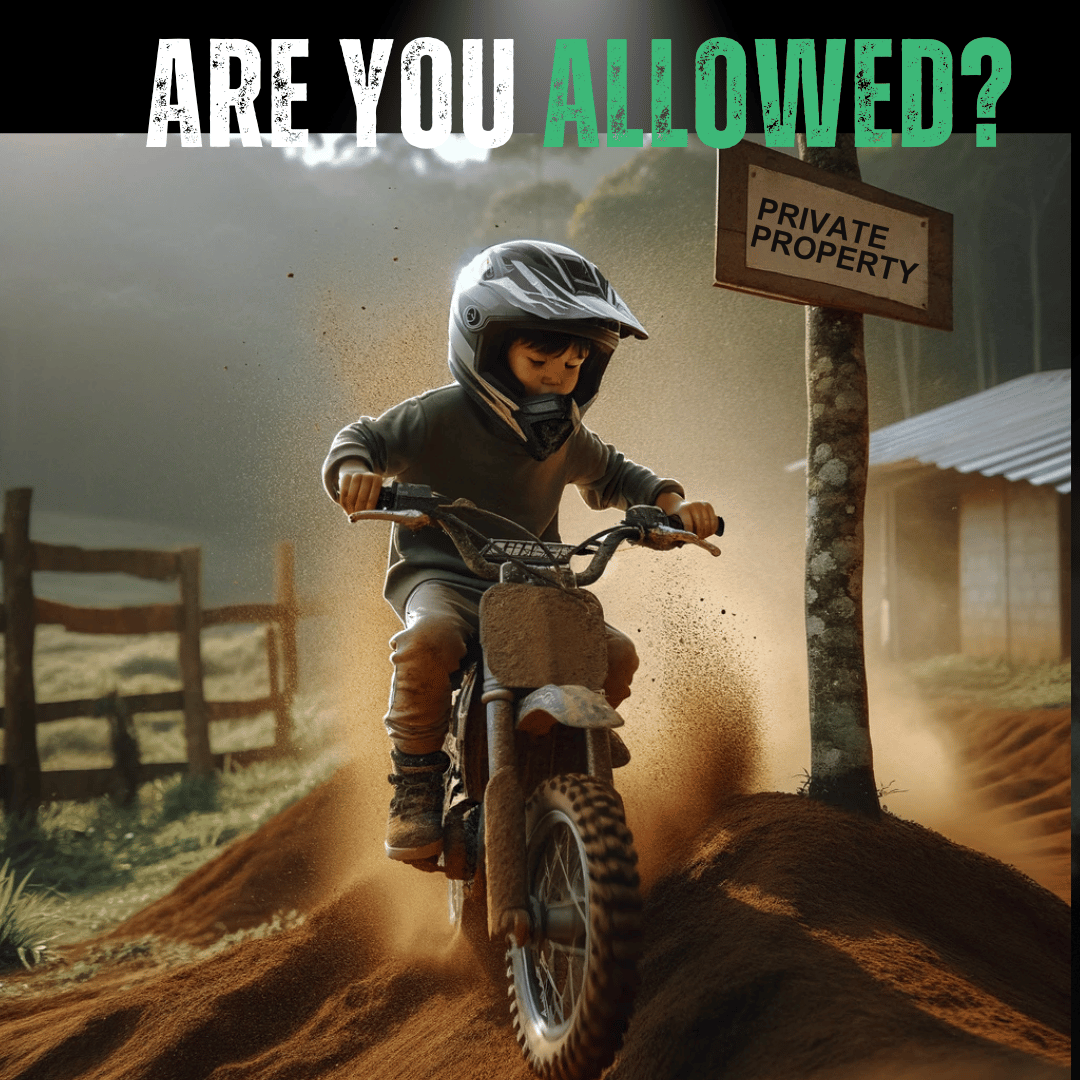 A photograph of a mixed-race child, wearing a safety helmet and rugged outdoor attire, actively riding a dirt bike over a small mound on private property