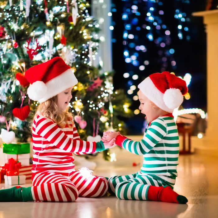 2 kids having fun around the christmas tree