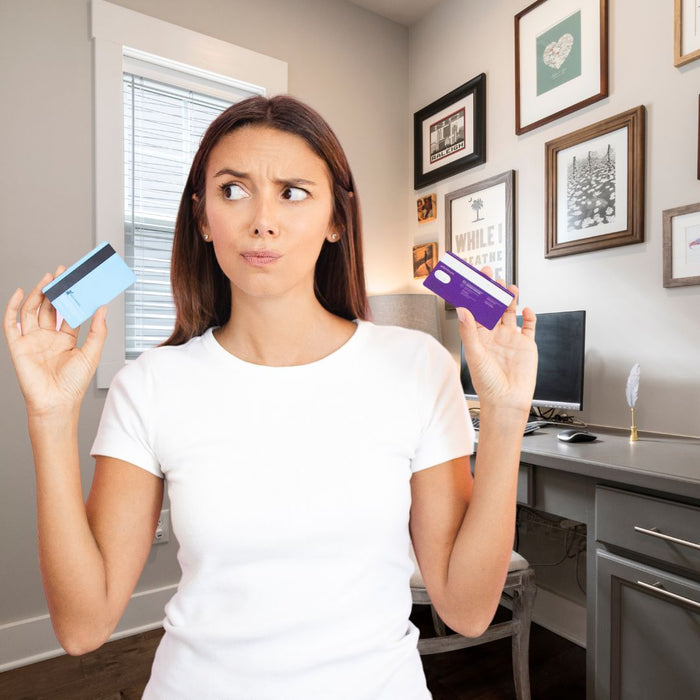a woman holding up two credit cards