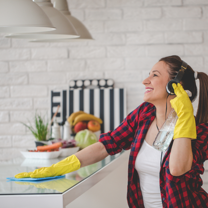 a woman Spring Cleaning with gloves wearing headphones
