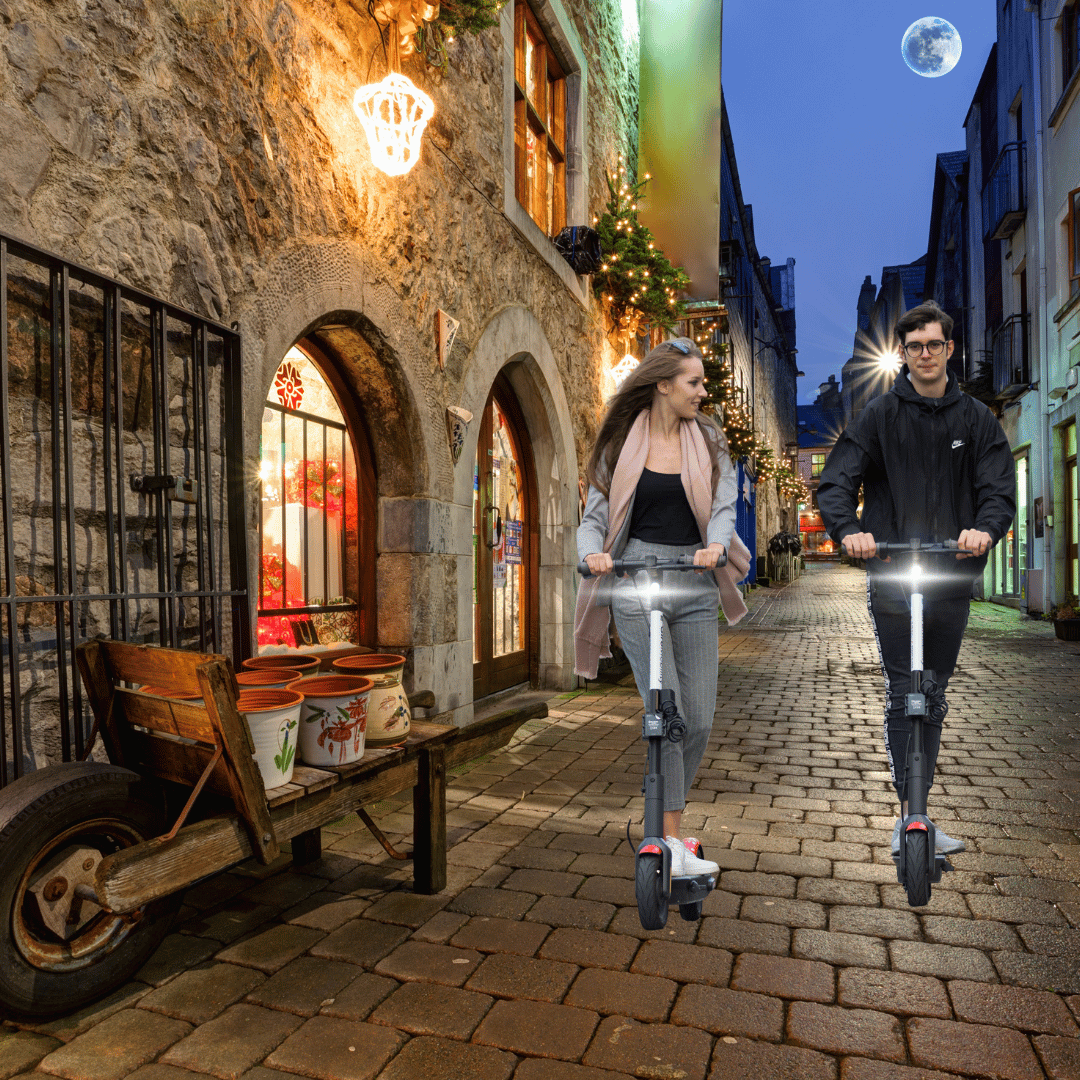 2 teens riding their escooter through the streets at night