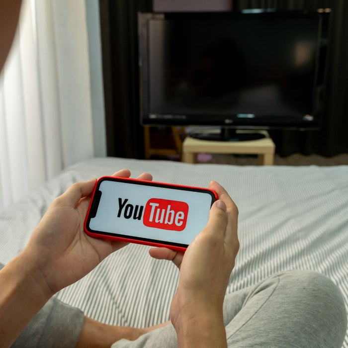 person holding a mobile with YouTube on the screen