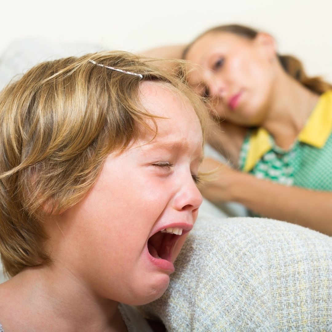 a child crying while mother looks on