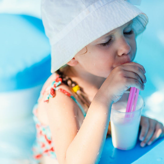 a child drinking milk at the pool with a straw