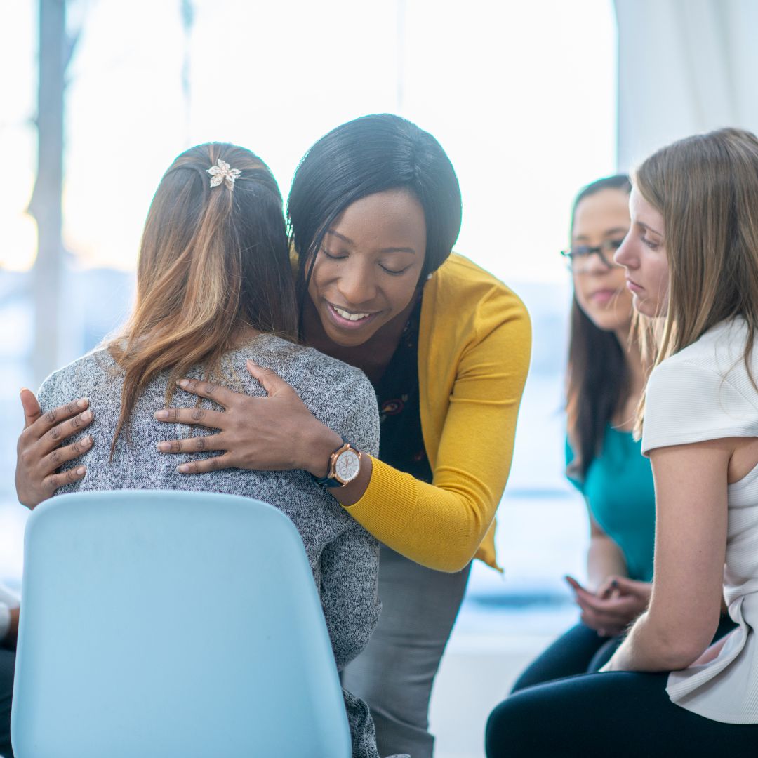 a mental health meeting with two women hugging