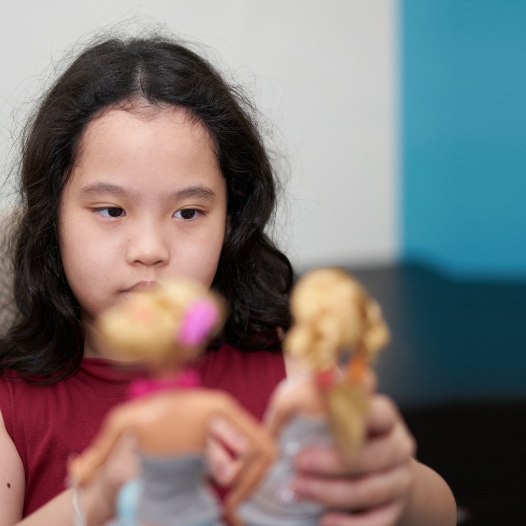 a small asian child playing with a doll