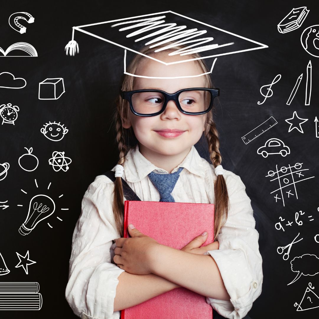 a young school girl against a blackboard holding a pink book