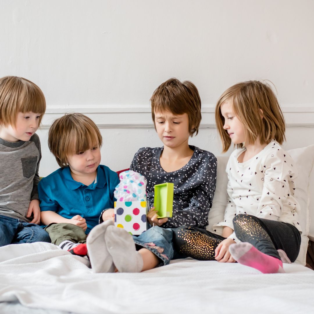 child getting gift from friends sitting on a bed
