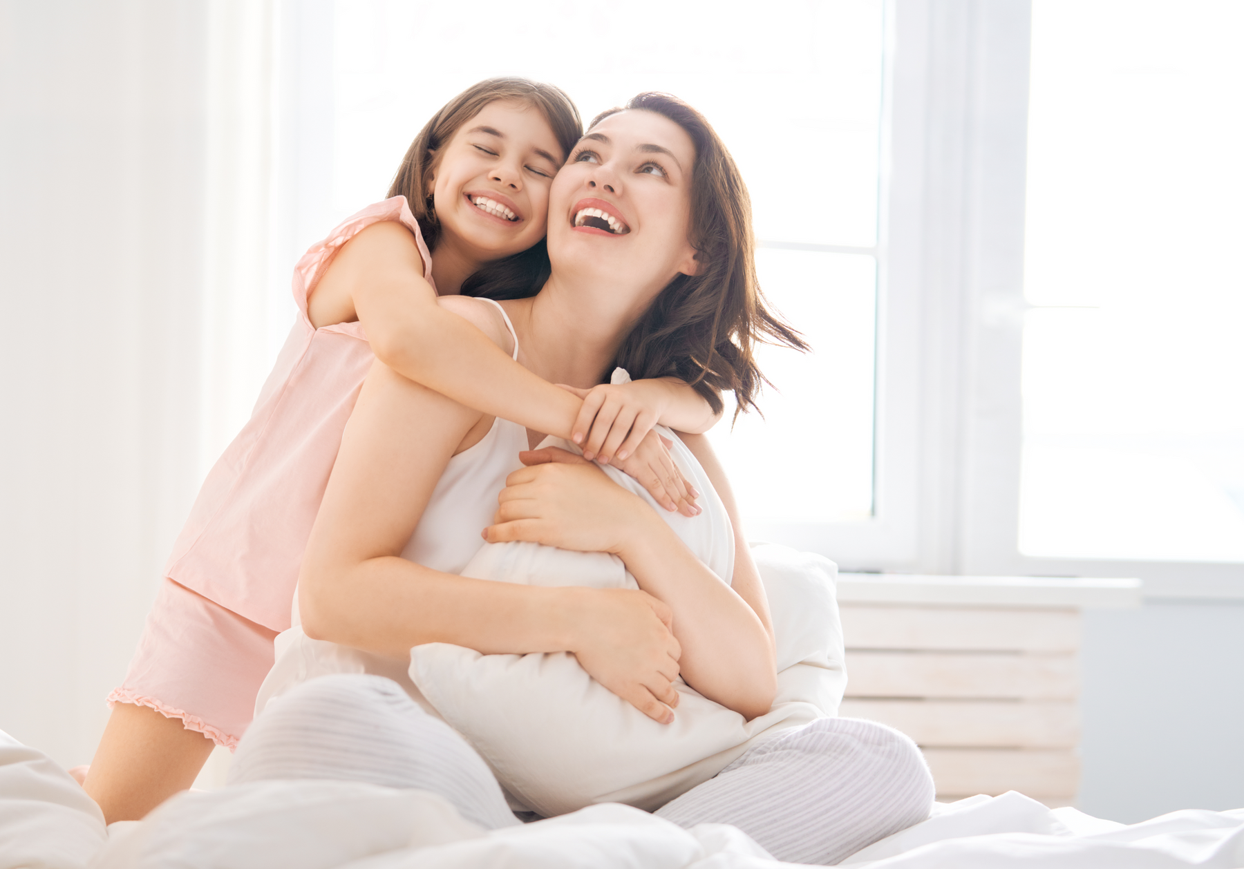 child cuddling her mother on a bed